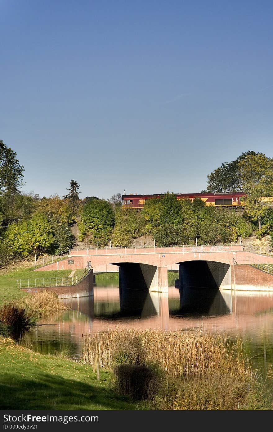 Autumnal scene of a Road Bridge in the foreground and a Railway bridge behind with a locomotive crossing. Autumnal scene of a Road Bridge in the foreground and a Railway bridge behind with a locomotive crossing.