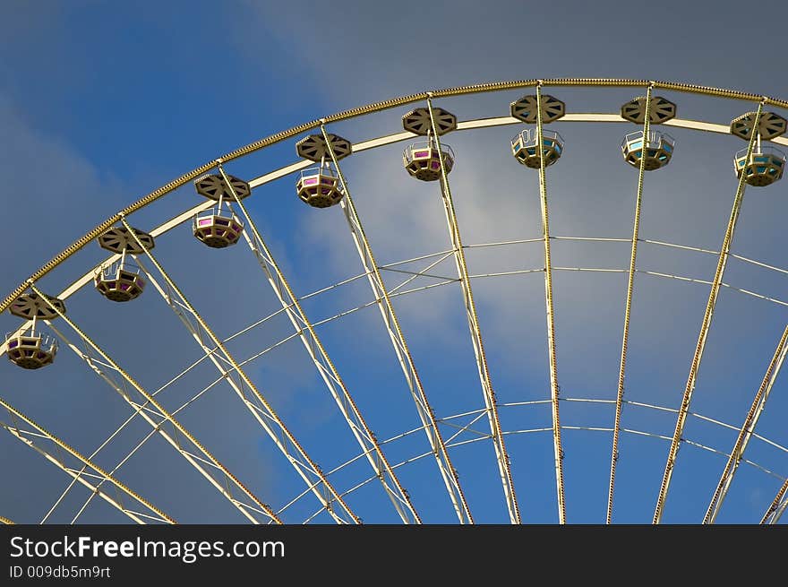 Close up of the big wheel at the local fair against blue cloudy background