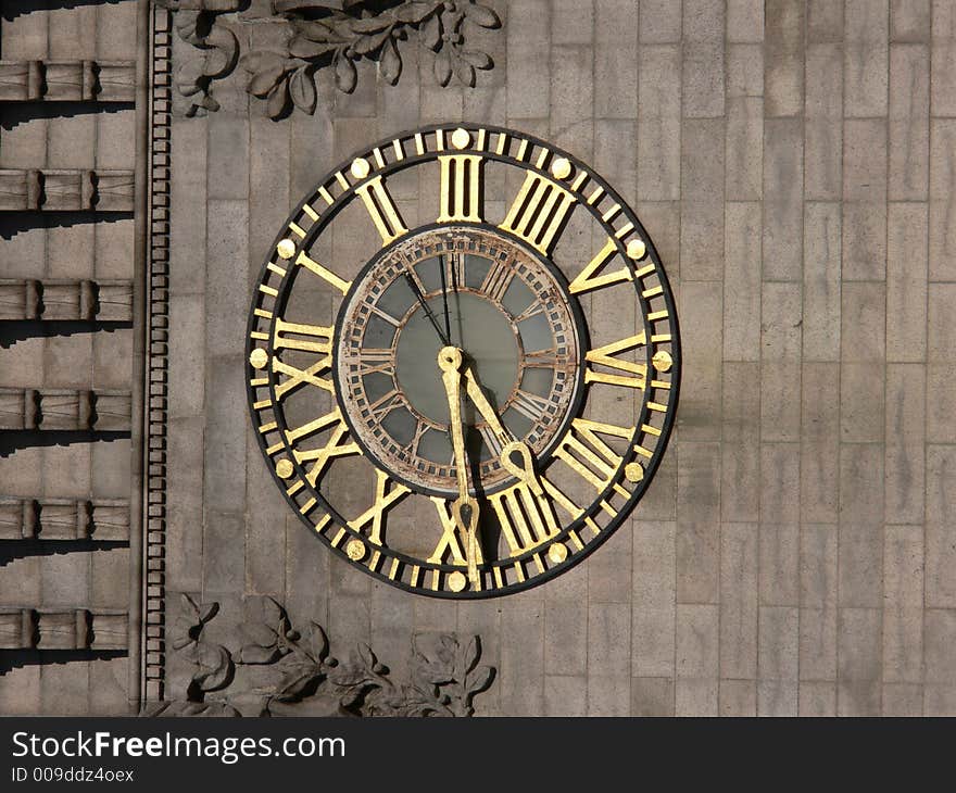 Antique Gold Clock on the face of an old building with ornate carvings. Antique Gold Clock on the face of an old building with ornate carvings