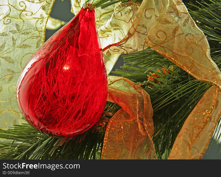 Red teardrop ornament against gold ribbon on Christmas Tree. Red teardrop ornament against gold ribbon on Christmas Tree