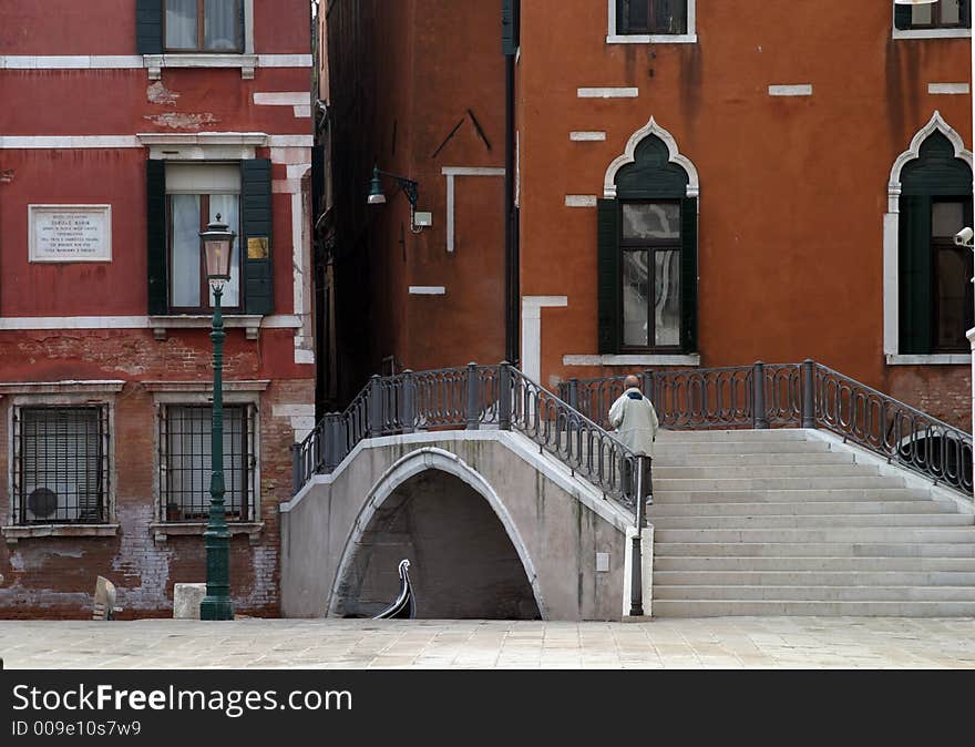 One man walking over a canal bridge in Venice. One man walking over a canal bridge in Venice.