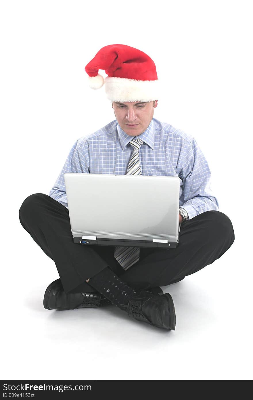 Businessman working on laptop with santa's hat over white. Businessman working on laptop with santa's hat over white