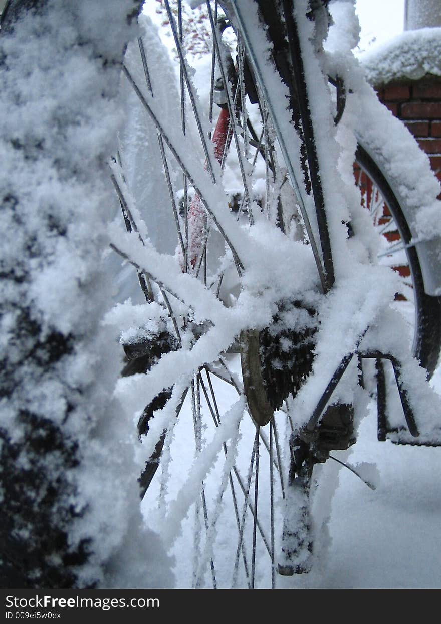 Covered with the snow bicycle is standing outdoors in the cold. Covered with the snow bicycle is standing outdoors in the cold.