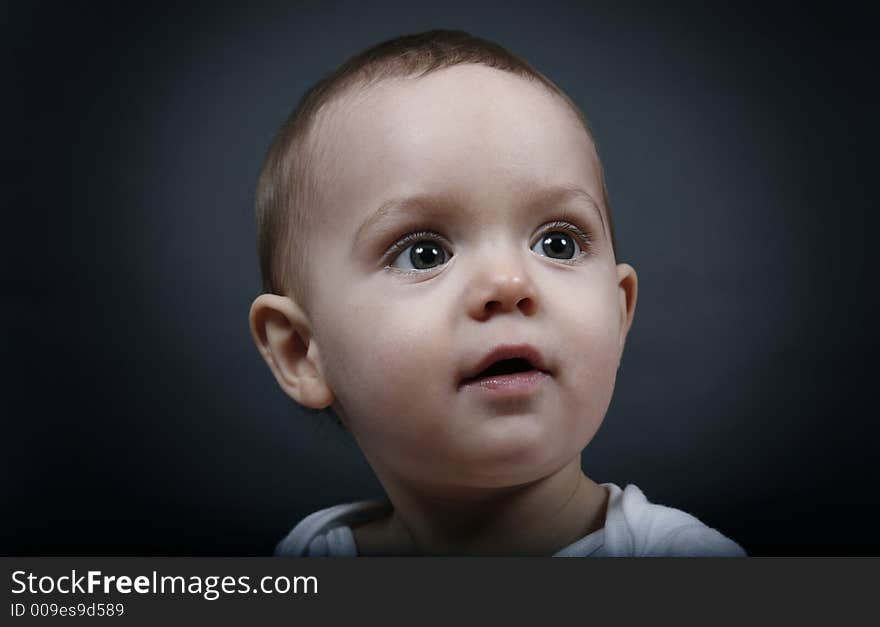 Beautiful baby boy poses on a black background