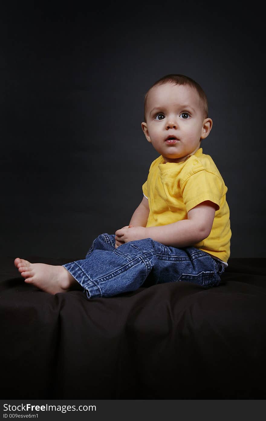 Beautiful baby boy poses on a black background