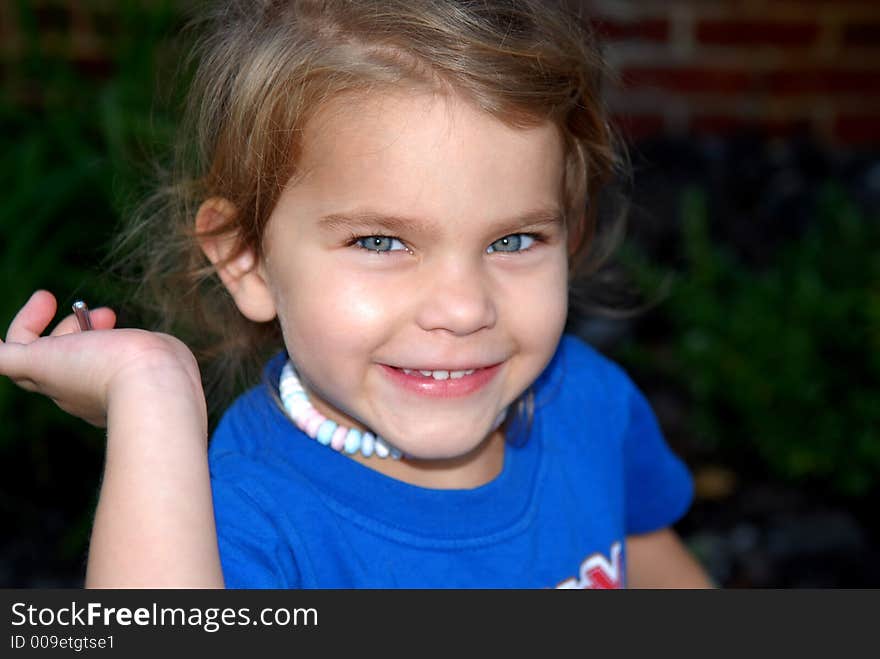 A pretty little girl with blue eyes and a big smile wearing a candy necklace. She's very happy and it shows on her face. A pretty little girl with blue eyes and a big smile wearing a candy necklace. She's very happy and it shows on her face.