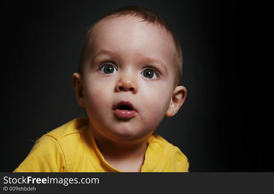 Beautiful baby boy poses on a black background