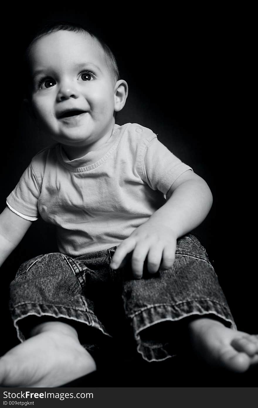 Beautiful baby boy poses on a black background