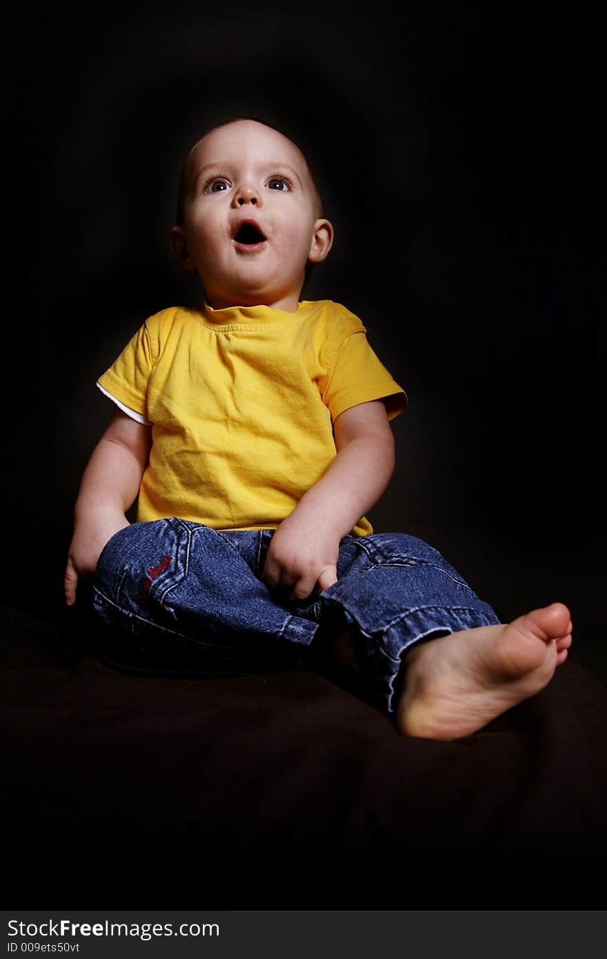 Beautiful baby boy poses on a black background