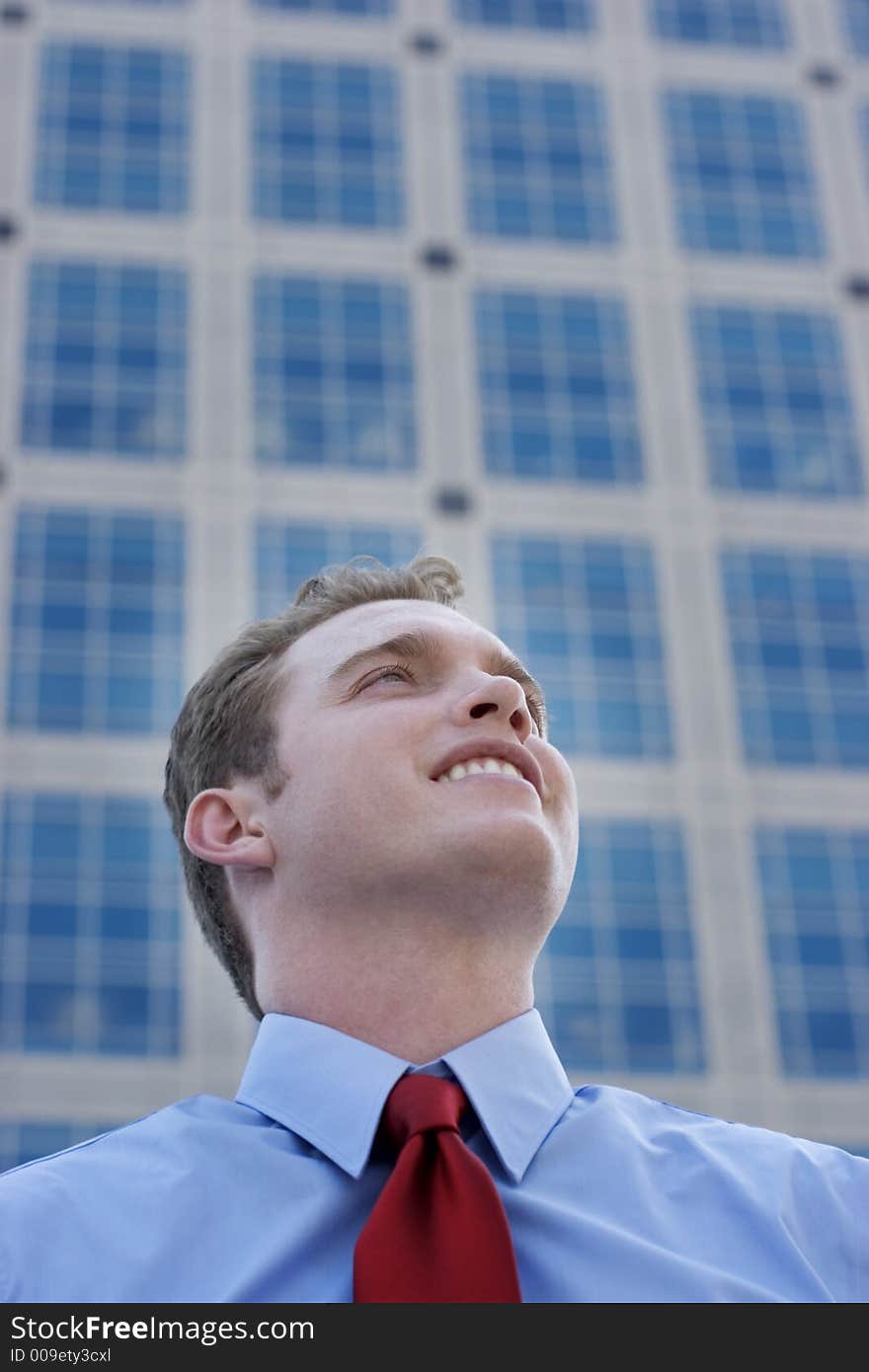 Businessman standing in front of a business building with a toothy smile and a red tie with a blue shirt. Businessman standing in front of a business building with a toothy smile and a red tie with a blue shirt