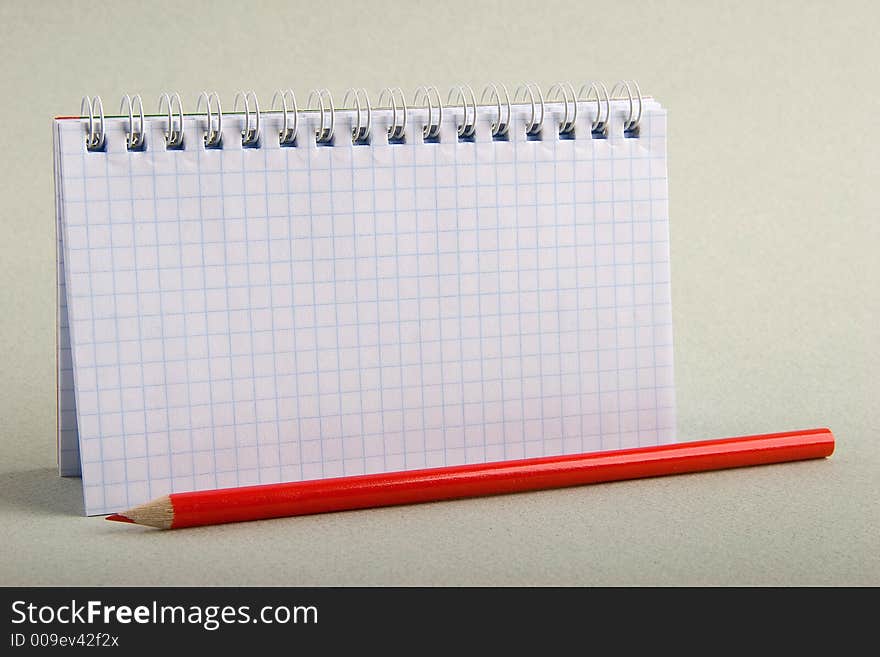 Notebook in a cell with a red pencil. Notebook in a cell with a red pencil