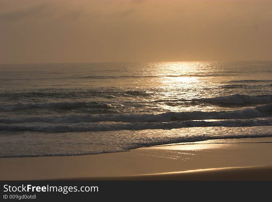 Sun rising over tropical beach with a light orange glow. Sun rising over tropical beach with a light orange glow