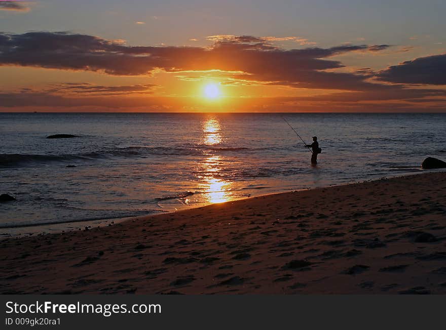 Fisherman surf-fishing at sunset on a rocky Atlantic Ocean beach. Fisherman surf-fishing at sunset on a rocky Atlantic Ocean beach.