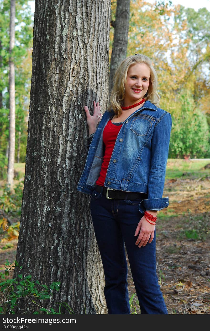 A beautiful girl wearing jeans and a blue denim jacket. She's also wearing a red shirt and a red necklace. A beautiful girl wearing jeans and a blue denim jacket. She's also wearing a red shirt and a red necklace.