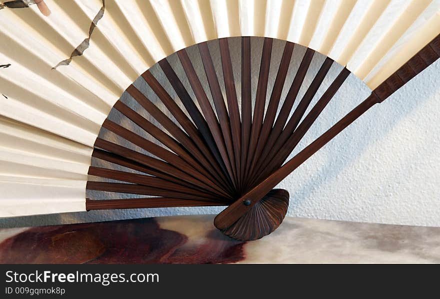 White, Beige Decorative Fan With Wood Grip On A Marble Table