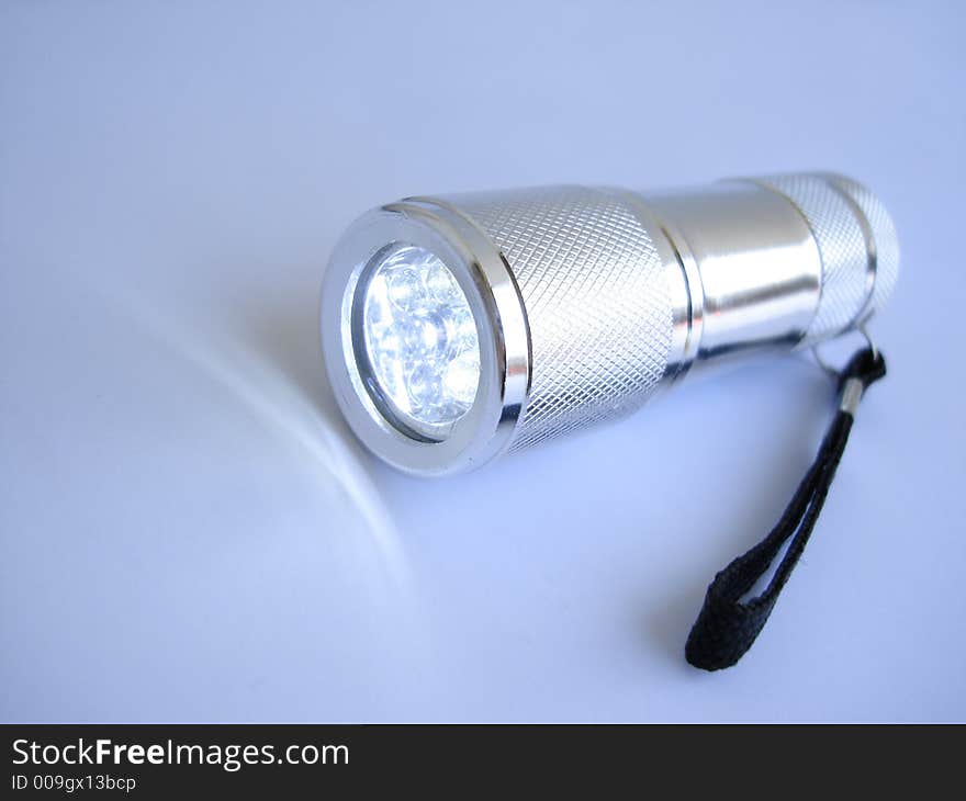 Silver metallic flashlight on blue background