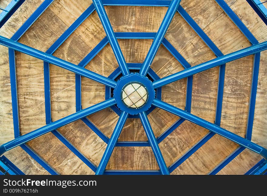 Architectural abstract-blue metal and wooden gazebo roof showing symmetry and resembling spider-web. Architectural abstract-blue metal and wooden gazebo roof showing symmetry and resembling spider-web