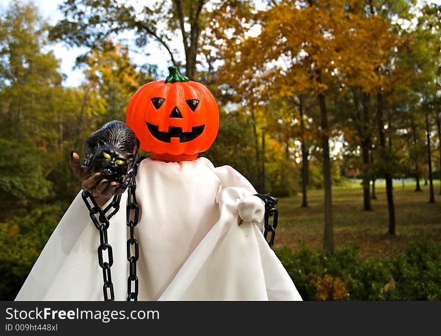 A pumpkin, jack-o-lanten headed Halloween doll made up to look like a ghost. A pumpkin, jack-o-lanten headed Halloween doll made up to look like a ghost.