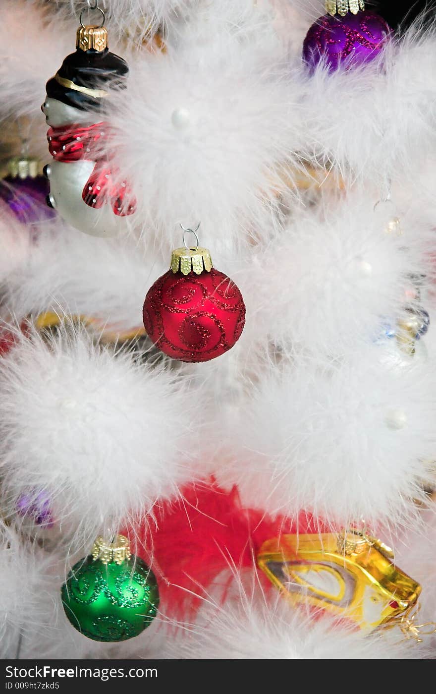 Christmas ornaments hanging on a white feather tree.