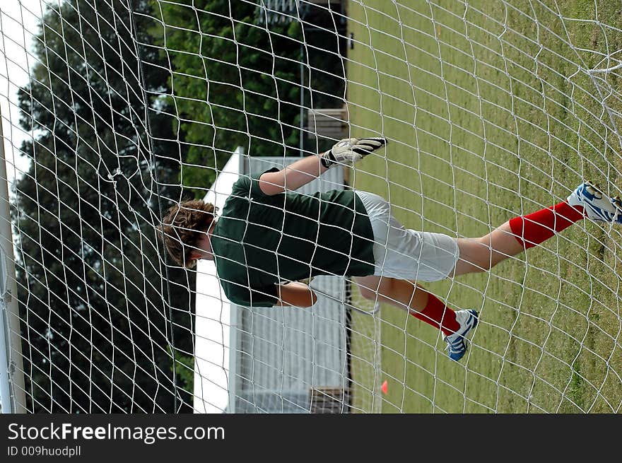 An active soccer goalie as seen through the net