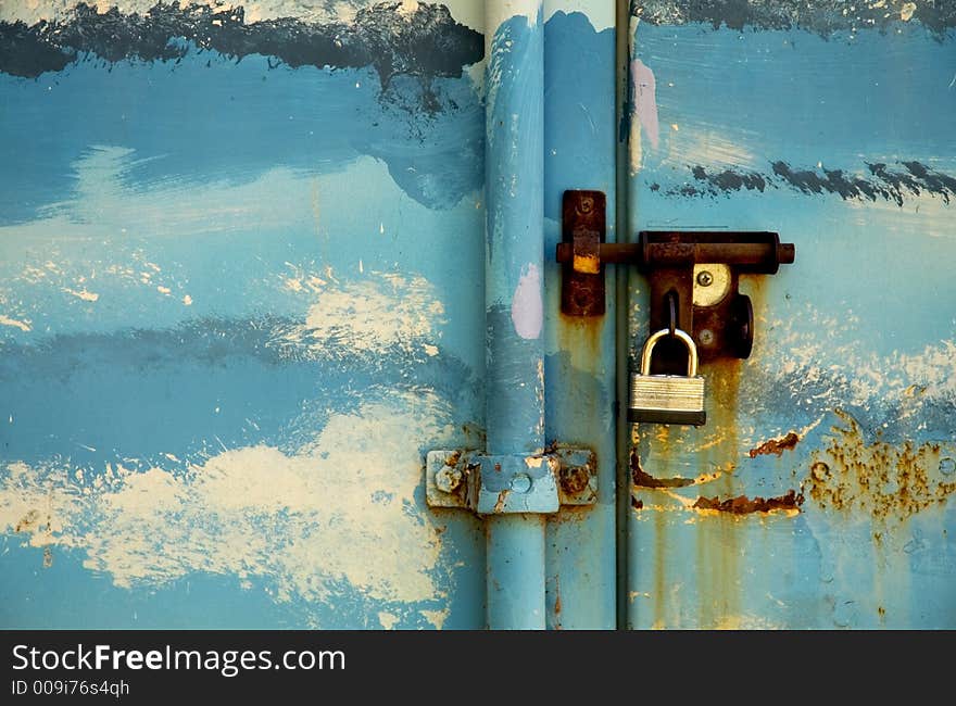 Steel storage locker decorated and painted like blue sky with clouds.  Rusty bolt and padlock. Steel storage locker decorated and painted like blue sky with clouds.  Rusty bolt and padlock.