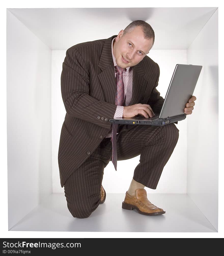 Businessman with laptop in the cramped white cube. Businessman with laptop in the cramped white cube