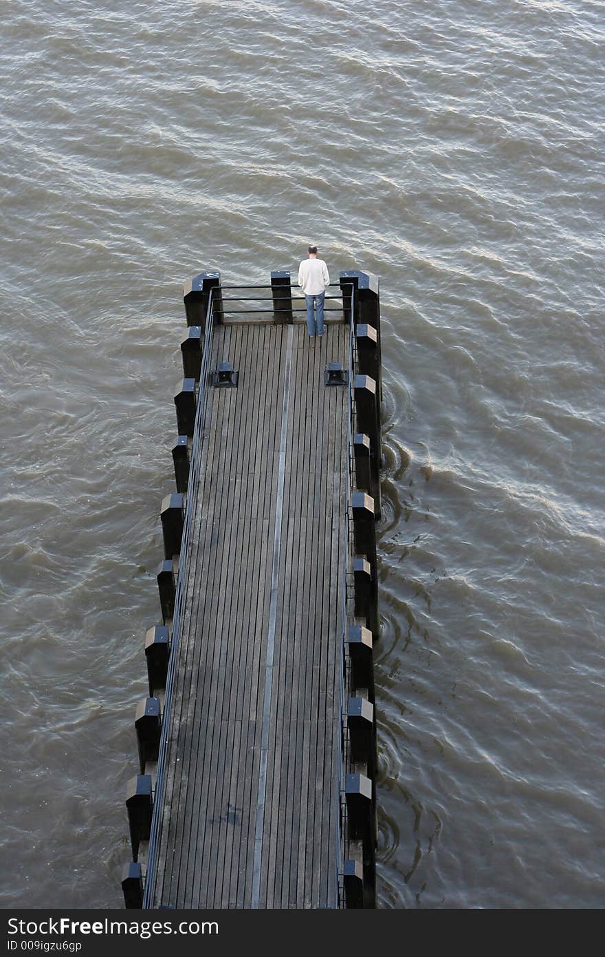 Man looking out at the end of a river pier in london. Man looking out at the end of a river pier in london