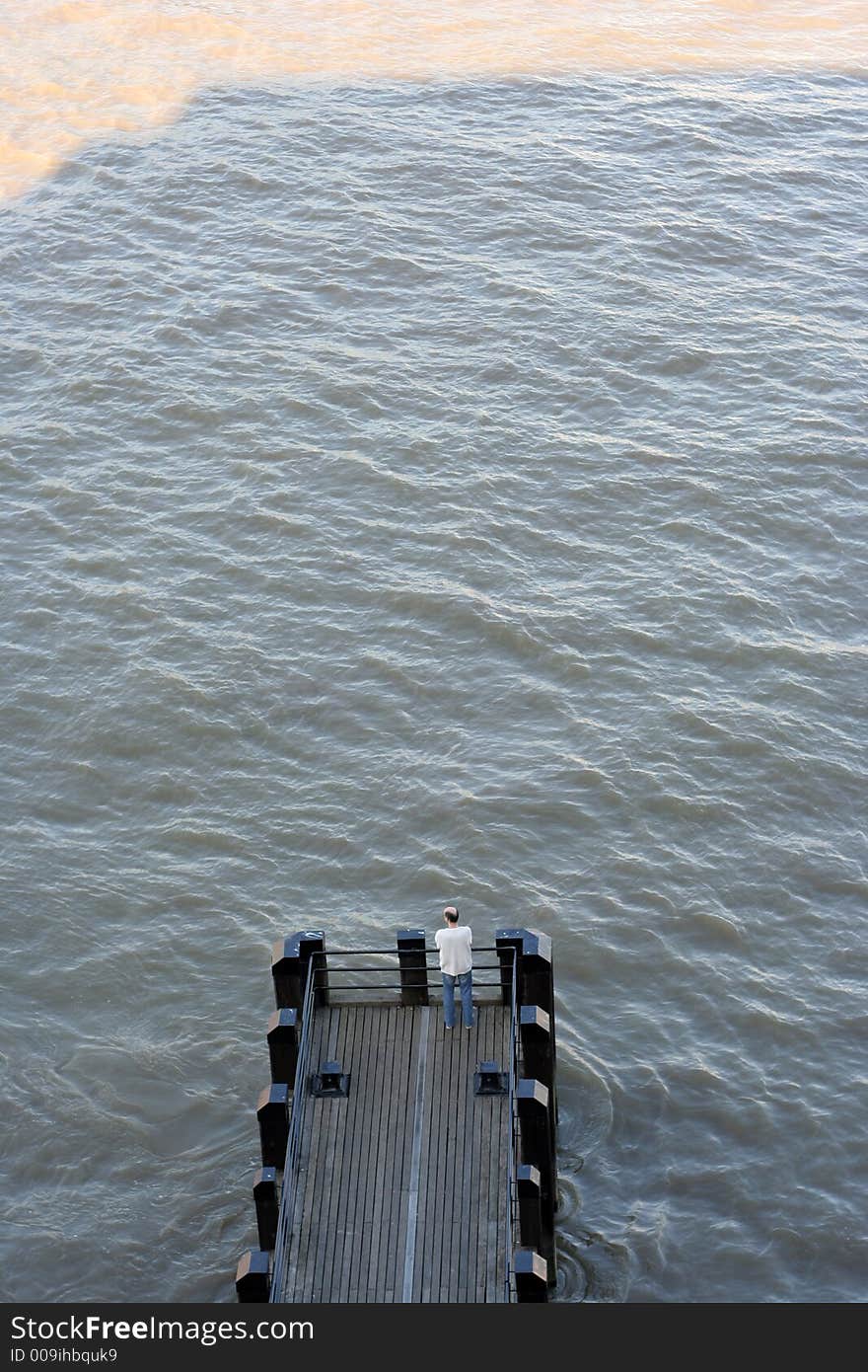 Man looking out at the end of a river pier in london. Man looking out at the end of a river pier in london