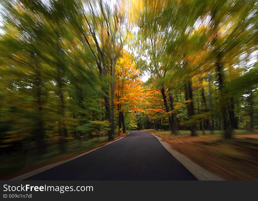 Driving along a blacktop road during the fall with motion blur. Driving along a blacktop road during the fall with motion blur