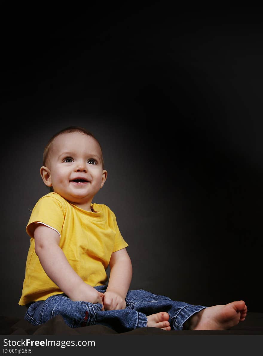 Beautiful baby boy poses on a black background