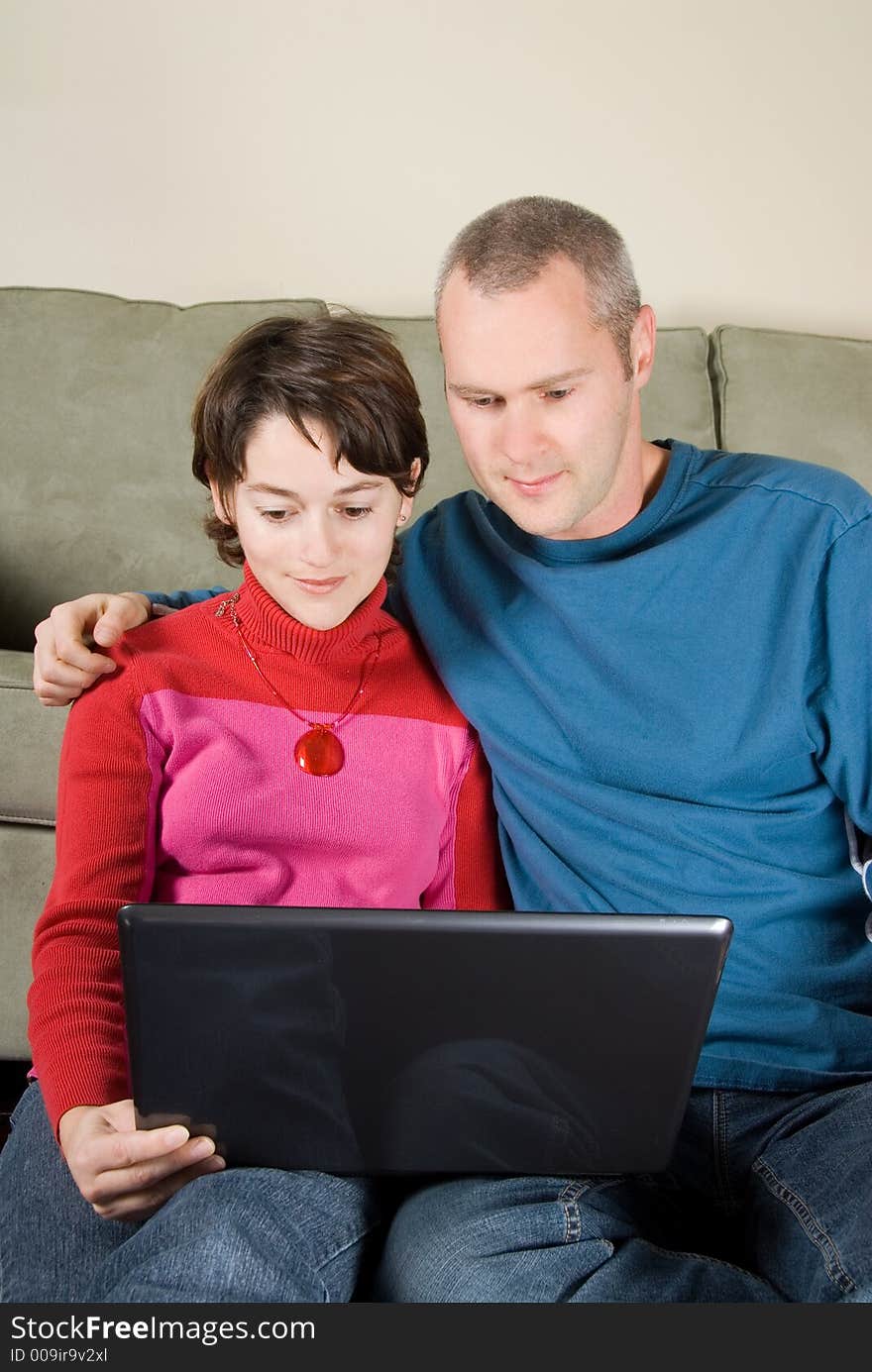 Pair leaning against the couch with laptop. Pair leaning against the couch with laptop