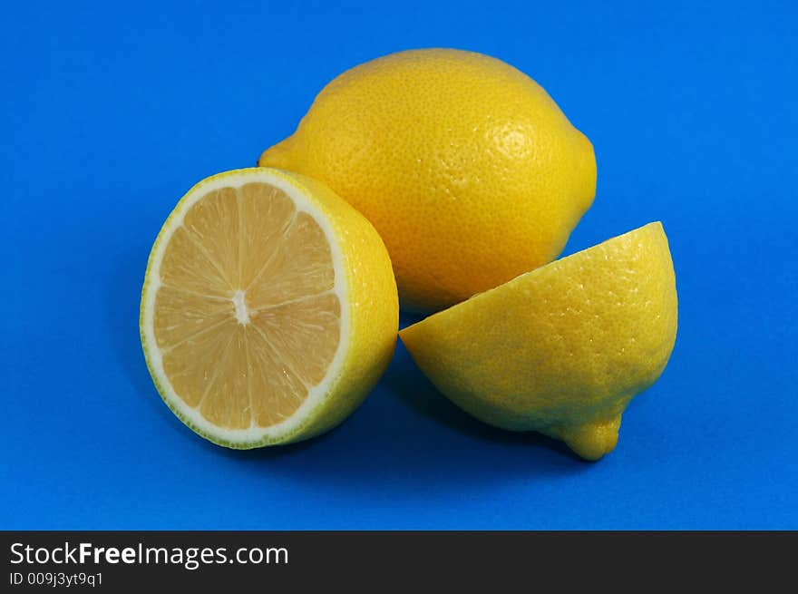 Whole and Cutted Lemons Over Blue Background. Whole and Cutted Lemons Over Blue Background