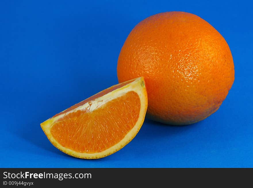 Whole Orange and Wedge Over Blue Background. Whole Orange and Wedge Over Blue Background