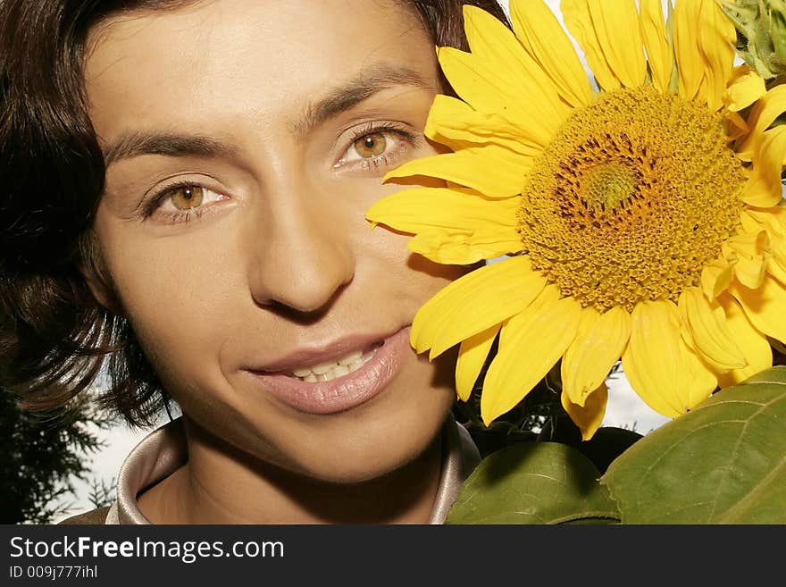 Portrait of a young woman, brunette with a sunflower-close up