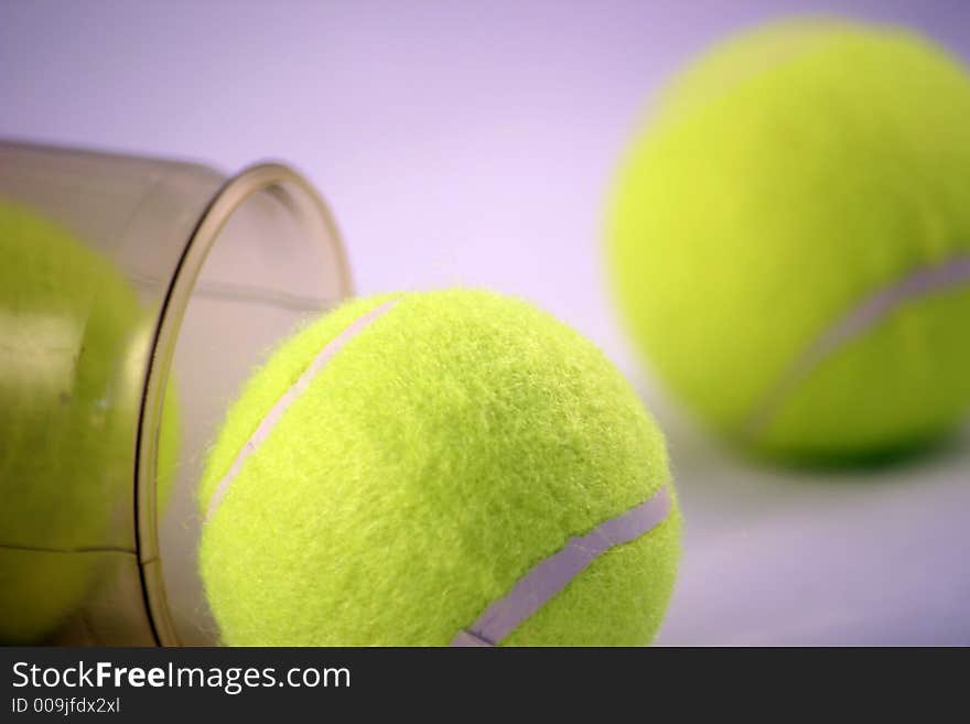 Three tennis balls emerging from the tube they are stored in