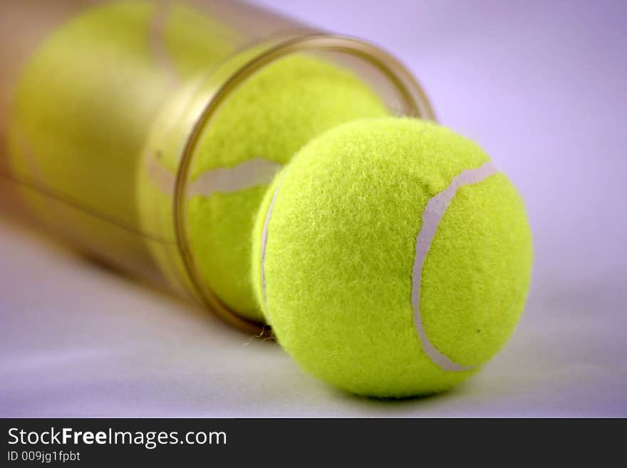 Three tennis balls emerging from the tube they are stored in