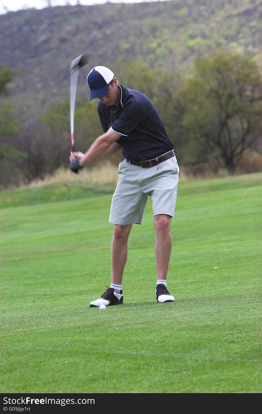 Golfer on down swing with a mid iron. Golfer on down swing with a mid iron