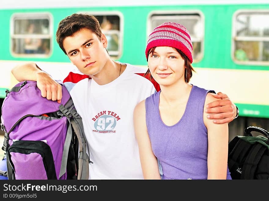 Girl and a boy travelling with backpacks-at a train station. Girl and a boy travelling with backpacks-at a train station