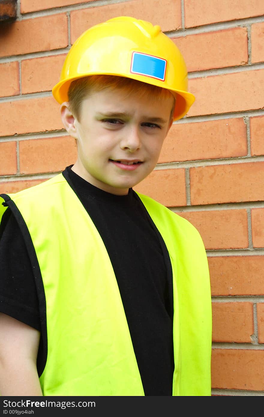 Boy playing workman in safety vest and hard hat