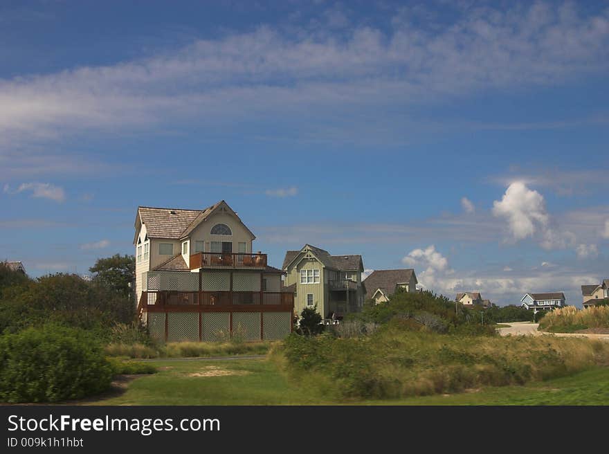 Beach homes on the coast amongst the green grass and blue skies. Beach homes on the coast amongst the green grass and blue skies