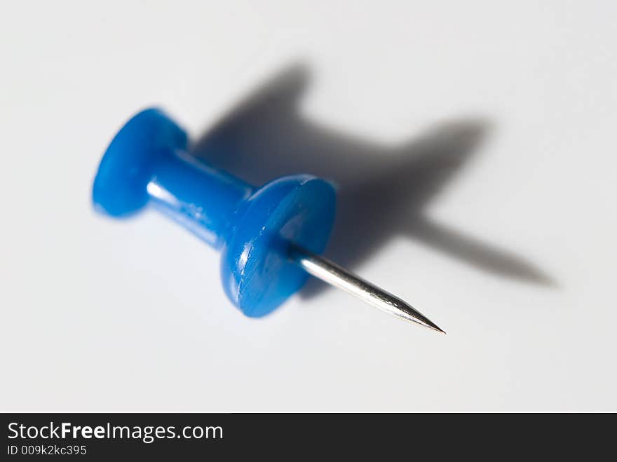 Plastic pin on grey background with long shadow. Plastic pin on grey background with long shadow