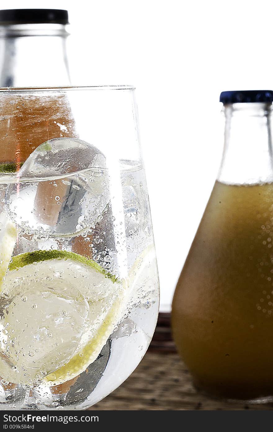 A glass of water with lemon and two bottled drinks in the background