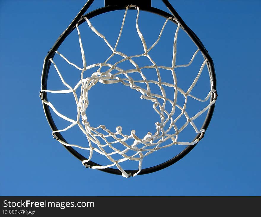 Shot of a basketball rim and net taken against the bright blue sky, looking up. Shot of a basketball rim and net taken against the bright blue sky, looking up.