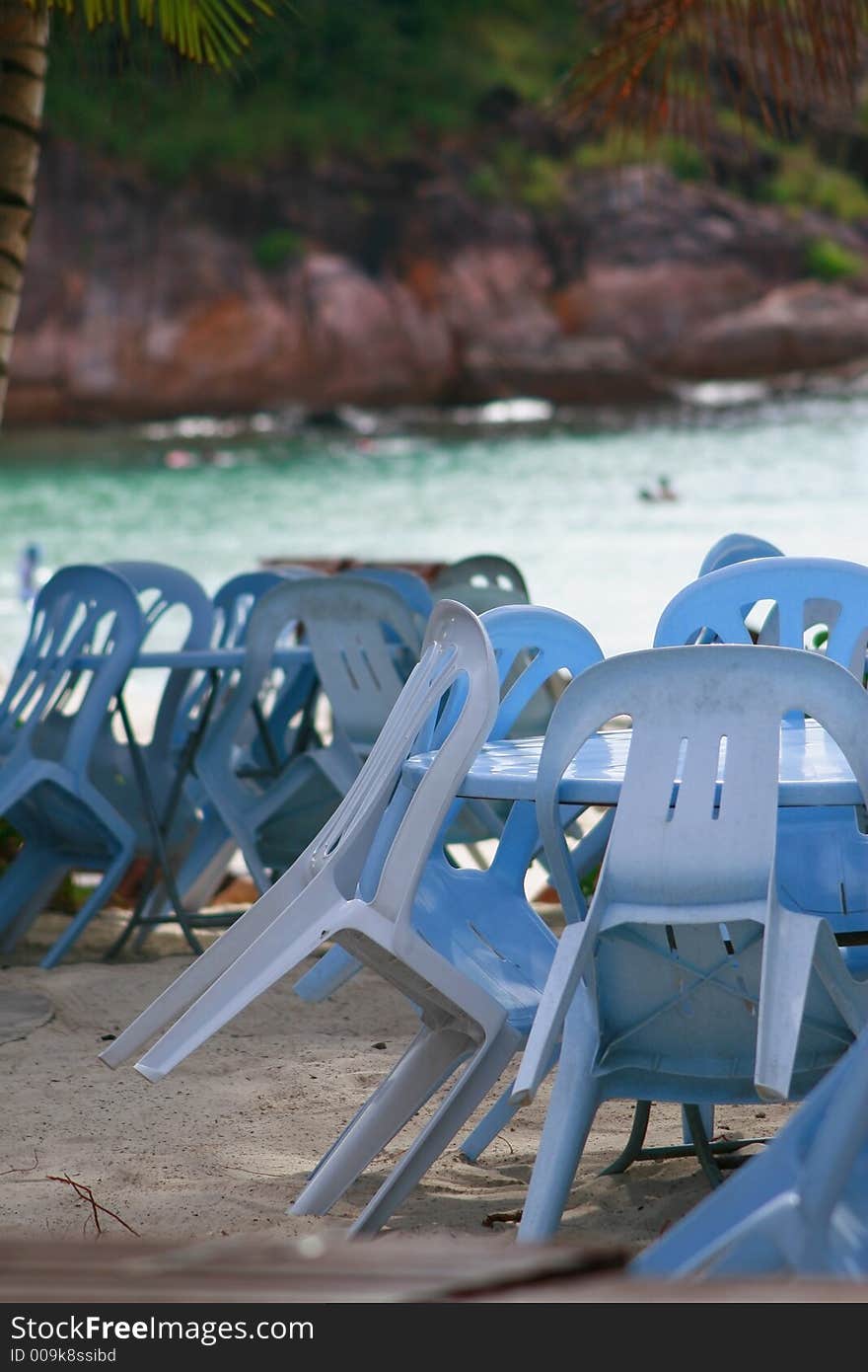 Tables & chairs by the beach provided by a beach restaurant for dining