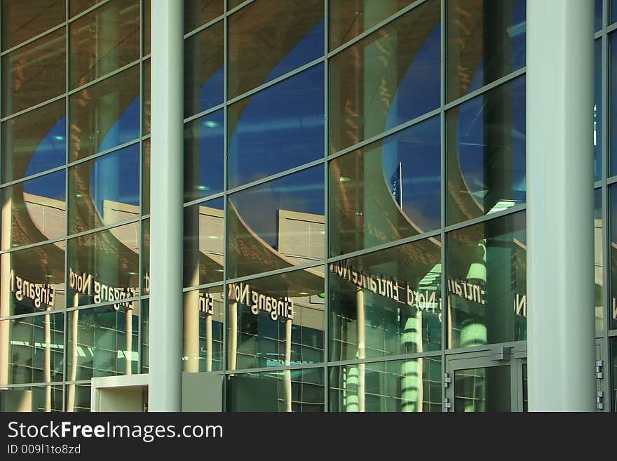 Reflection of the blue sky and part of a building in glasses of a facade creates abstraction