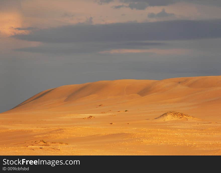 Sand Dunes Against A Stormy Sky