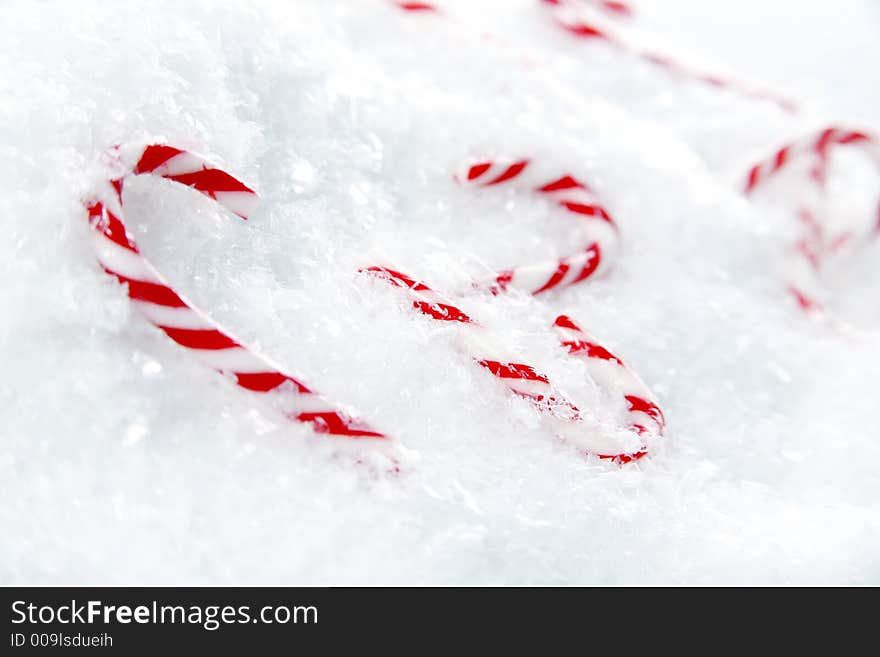 Miniature candy canes in a pile of snowflakes. Miniature candy canes in a pile of snowflakes