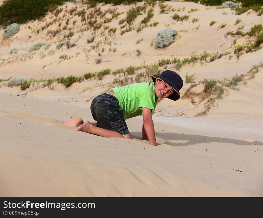 A boy plays in the sand on a large sand dune whilst on holiday. A boy plays in the sand on a large sand dune whilst on holiday