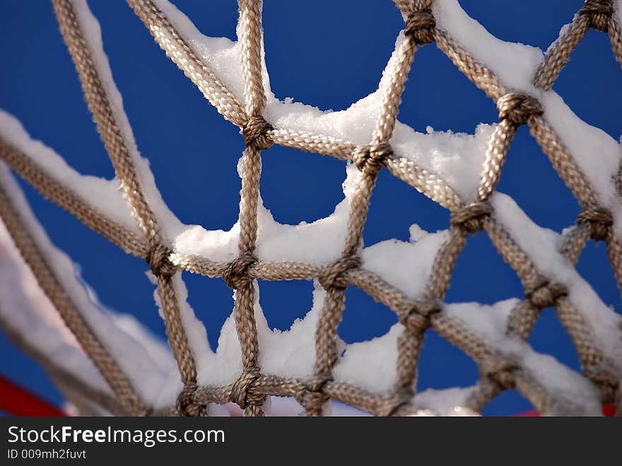 Snow sits on an unused basketball net. Snow sits on an unused basketball net.