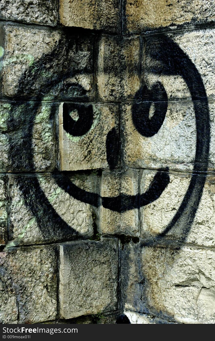 Illegal graffiti - a smiley face spray-painted in a corner of a stone wall. Illegal graffiti - a smiley face spray-painted in a corner of a stone wall.